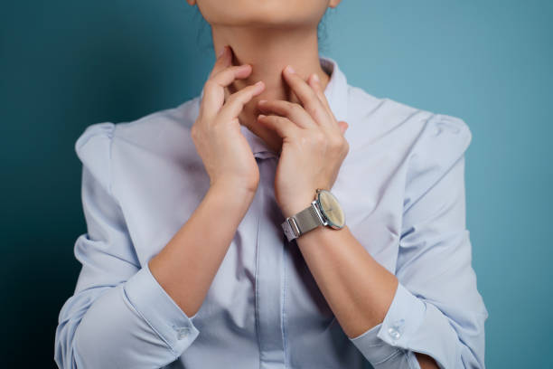 Woman was sick with sore throat. Woman was sick with sore throat isolated on blue background. Close up shot. thyroid disease stock pictures, royalty-free photos & images