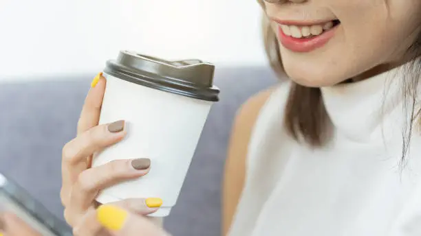A coffee mug in the hand of a girl who is about to drink