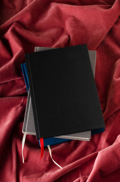 istock Stack of blank covers of books on the pink fabric surface.Empty space for design 1295933740