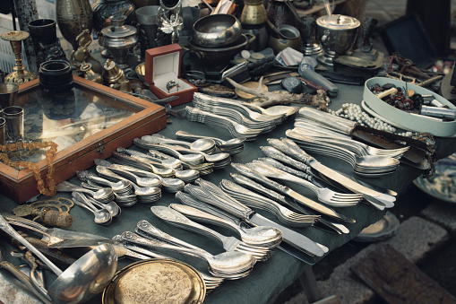 Antiques on flea market or festival, aged vintage silver cultery - spoons, knifes, forks, and other vintage things. Collectibles memorabilia and garage sale concept