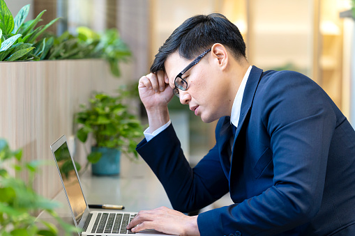 Young businessmen are stressed over earnings on laptops. Tired or stressed businessman sitting in front of laptop in Co-Working space.