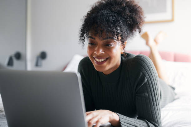 istock Woman lying on bed working from home on laptop computer 1295936484