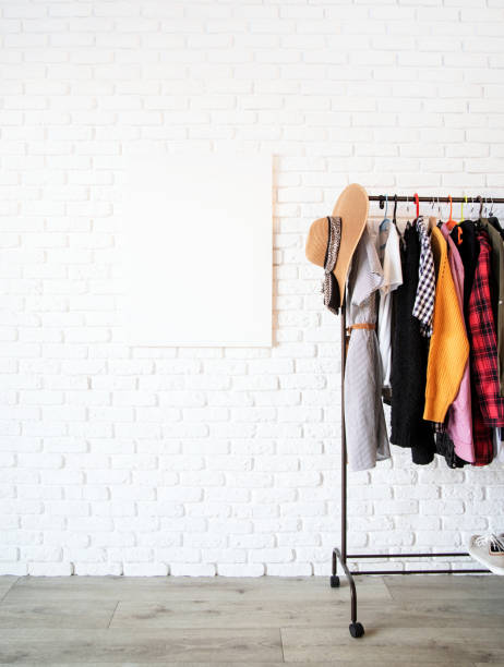 istock Rack with colorful clothes on hangers and frame canvas for mock up over white brick wall background 1295936671