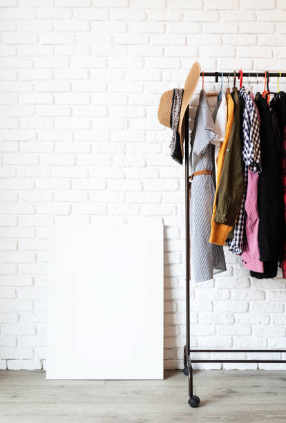 istock Rack with colorful clothes on hangers and frame canvas for mock up over white brick wall background 1295936730