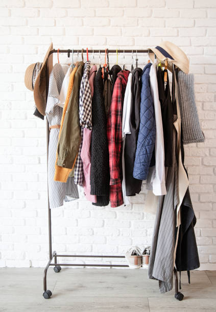 istock Rack with colorful clothes on hangers over white brick wall background 1295936778