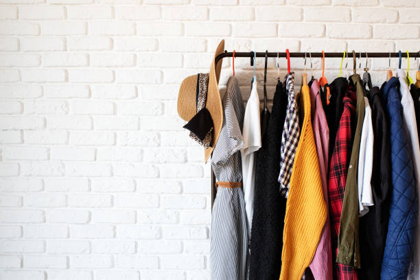 istock Rack with colorful clothes on hangers over white brick wall background 1295936940