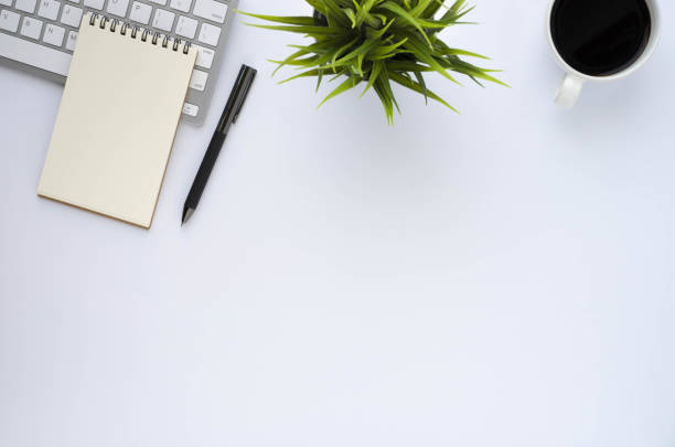 istock Top view above of White office desk table with keyboard, notebook and coffee cup with equipment office supplies. Business and finance concept. Workplace, Flat lay with blank copy space. 1295938056