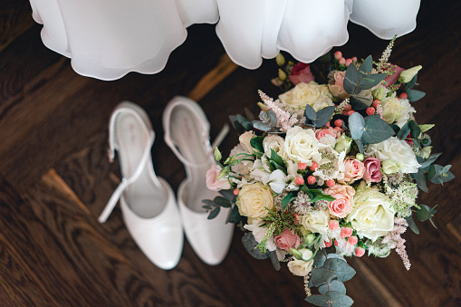 Bridal bouquet with bridal shoes and wedding dress