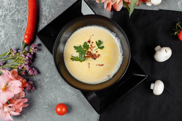istock Cheese soup in a black plate on gray background 1295940332