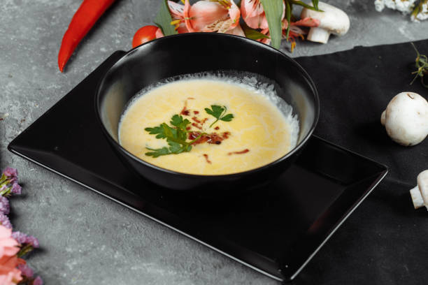 istock Cheese soup in a black plate on gray background 1295940499