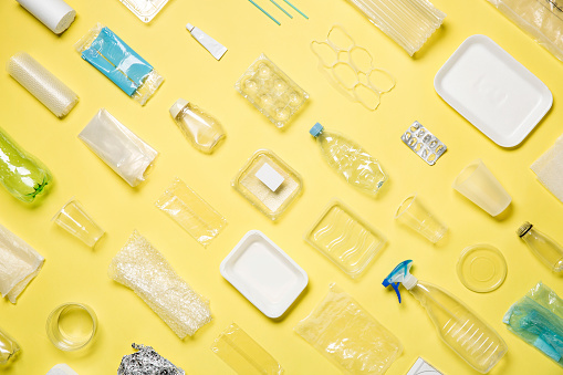 Different types of used plastic packaging arranged on a yellow background