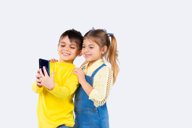 crianças felizes da pré-escola com vídeo de smartphone chamando e sorrindo em fundo branco. - telephone child isolated on white elegance - fotografias e filmes do acervo