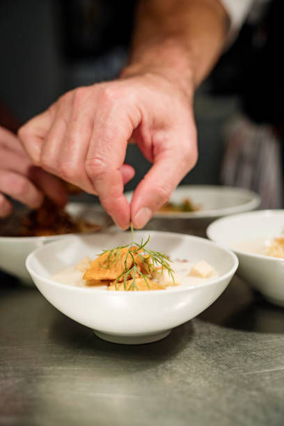 istock Chef preparing a bow of Jerusalem Artichoke soup at the pass. 1295946586