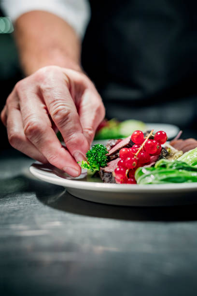 istock Chef at the pass adding the final touch to a dish of venison with seasonal vegetables. 1295947018