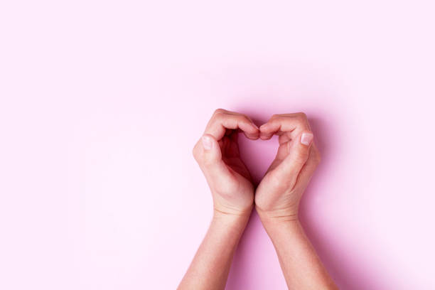 istock Hands show a heart on a pink background. Valentine's day concept. Empty space 1295947100