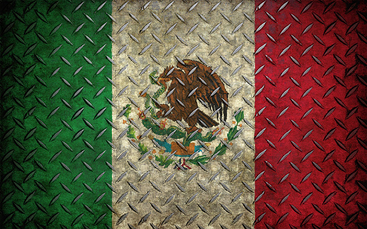 San Jose del Cabo Centro, Mexico - July 16, 2023: Closeup of the open National Mexican flag itself set against blue sky. Some green foliage in corner