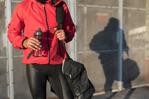 Close up of sporty man holding bottle of water before urban outdoor workout.