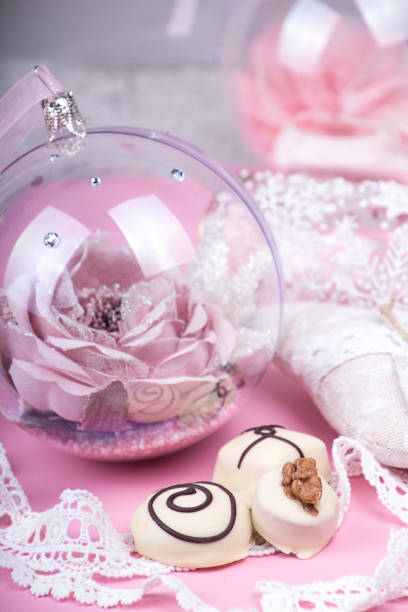istock Christmass New Year decorations. Greeting card. White chocolate candy, Christmass ball. Tender pink and gray color. 1295949320