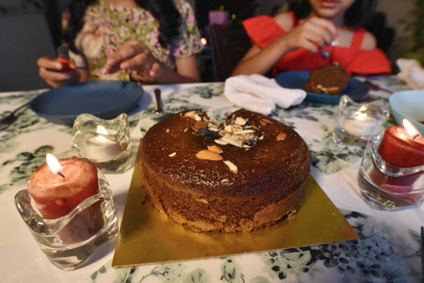 istock Girls enjoying plum cake on a dining table illuminated with candles on the table 1295950167