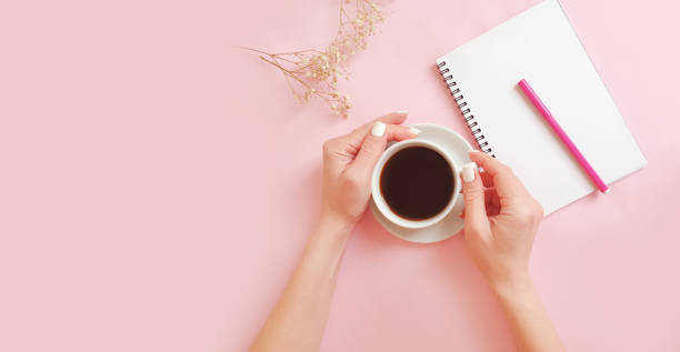 istock female hands holding a cup of coffee, notebook on a colored background 1295950206