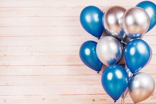 silver and blue balloons on wooden background. Concept of happiness, joy, birthday. Copy Space