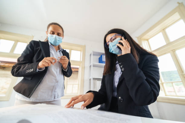 istock The New Normal. New office setup. Two colleagues wearing protective face masks working together in the office while COVID-19 pandemic. 1295952980
