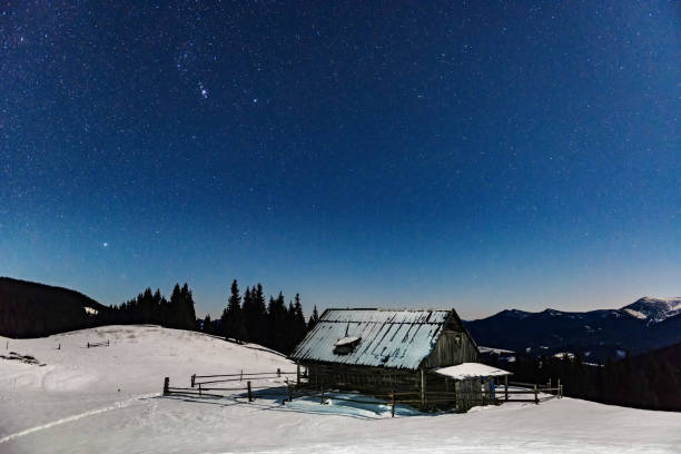 istock Night starry sky over lone cabin in the mountains 1295954419