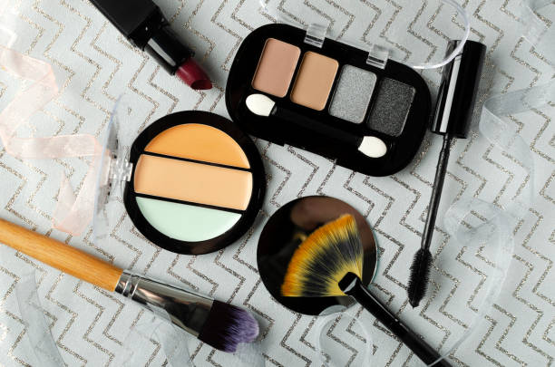 Top view of ribbons, decorative cosmetics and brushes for makeup on the grey surface