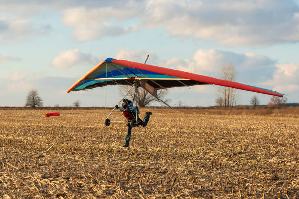 Hang gliding student runs fast Hang gliding student runs fast with her wing. Learn to fly. glider hang glider hanging sky stock pictures, royalty-free photos & images