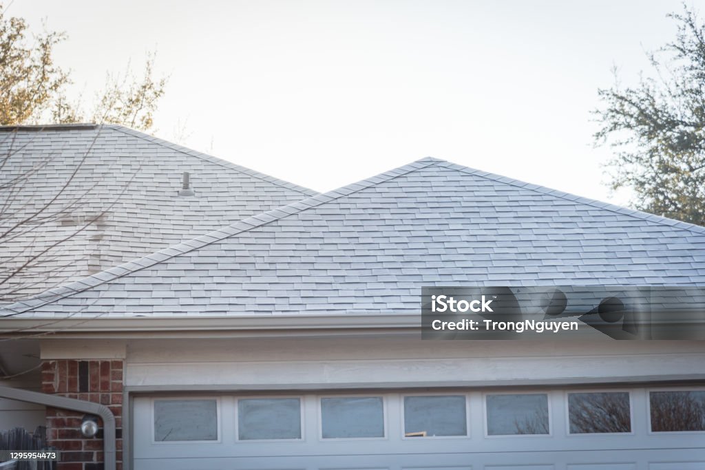 Icy roof shingles in early winter morning at suburban residential house in Coppell, Texas, USA Frozen and light snow on roof shingles of suburban residential house near Dallas, Texas, America Asphalt Stock Photo