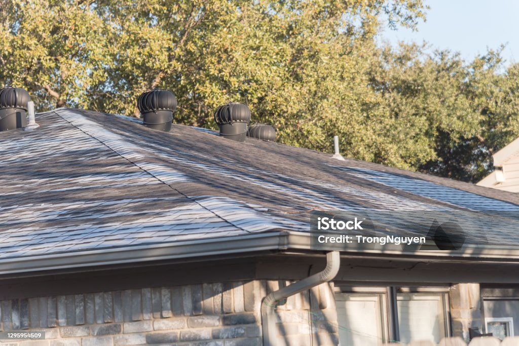 Snow melting on roof shingles of suburban residential house in Coppell, Texas, USA Light snow melting on shingles roof of residential house near Dallas, Texas, America Asphalt Stock Photo