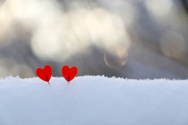 istock Two love hearts on the snow in sunlight 1295955242