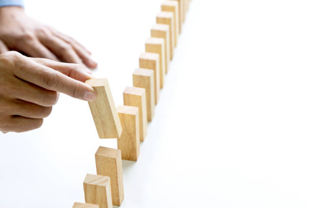 Young man holds the wood block in his hand to put it into the row Young man holds the wood block in his hand to put it into the row to protect the domino effect business concept put down stock pictures, royalty-free photos & images