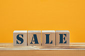 wooden blocks with the wordings SALE, isolated against yellow background