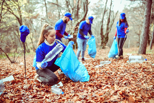 Female Picking Up Plastic Bottles From Forest