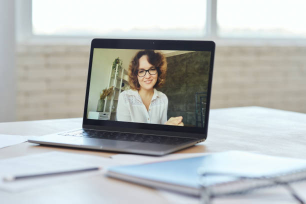 istock Female teacher smiling at camera during video call while having online lesson with schoolchildren studying from home 1295966197
