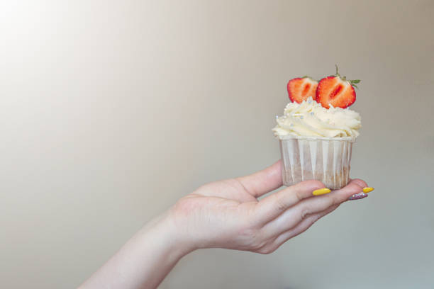 istock cupcake with white cream decorated with strawberries in the hand 1295966774
