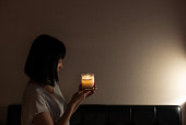 アジアの女性が夜に自宅のキャンドルライトを見つめている。