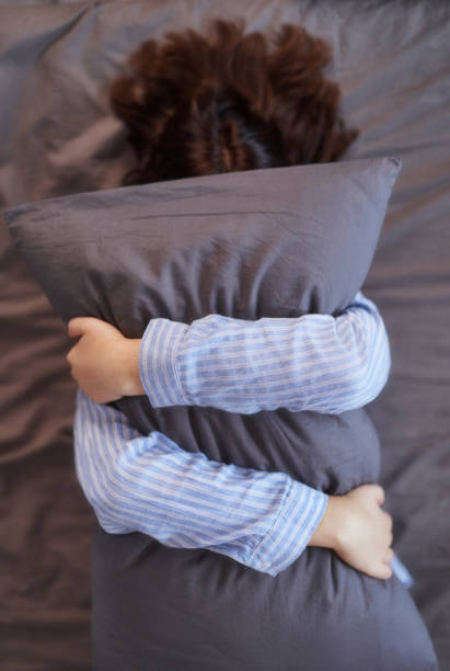 istock Woman lying on bed and covers her face with pillow 1295969380