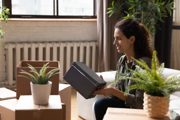 istock Smiling woman pack boxes on moving day 1295970416