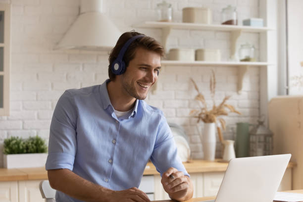 istock Smiling man in headphones watch webinar on laptop 1295970465