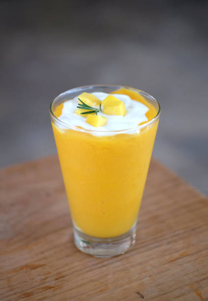 Mango smoothies and yogurt on top in a glass. Tropical fruit summer drink.
