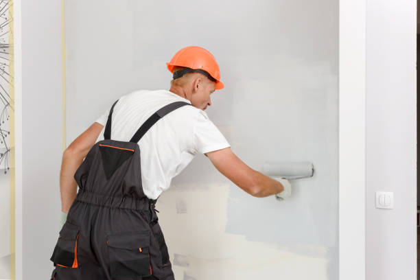 istock The painter is painting a wall in a room with a roller. 1295971476
