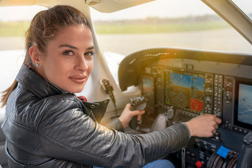 Portrait of Female Pilot in the Light Aircraft Cockpit. Woman Looking at Camera from the Cockpit of a Private Plane.