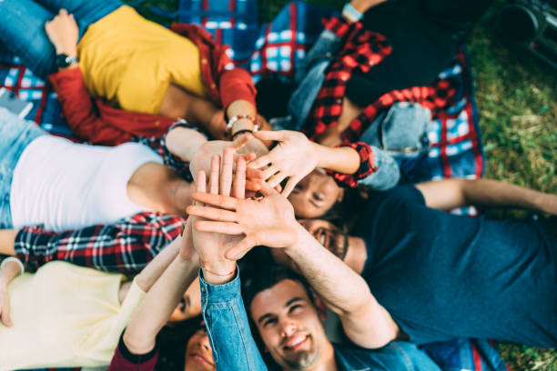 istock Friends at picnic blanket putting hands together 1295980158