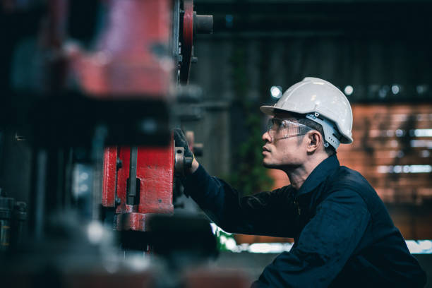 мужчины промышленного инженера носить белый шлем, стоя на тяжелой промышленной фабрике позади. обслуживание глядя работы на промышленное � - machine стоковые фото и изображения