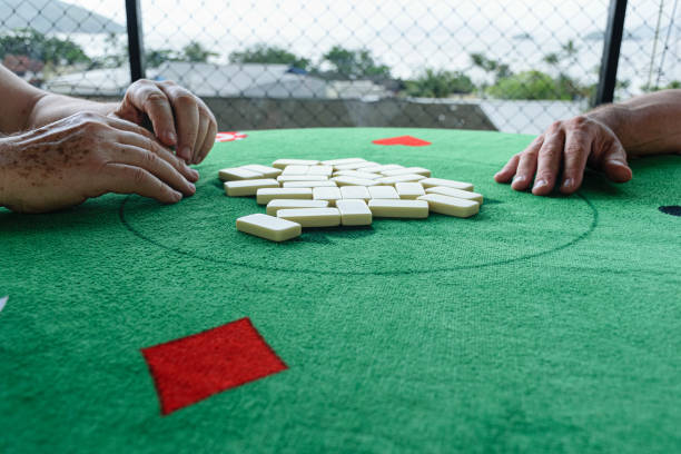 istock Two men picking up their pieces to start a domino game. 1295983050