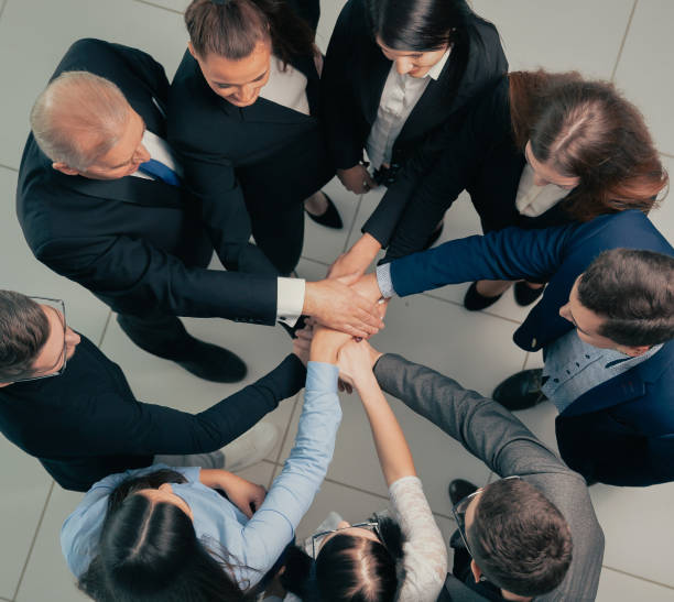 istock top view. boss and business team making a stack of hands 1295983432
