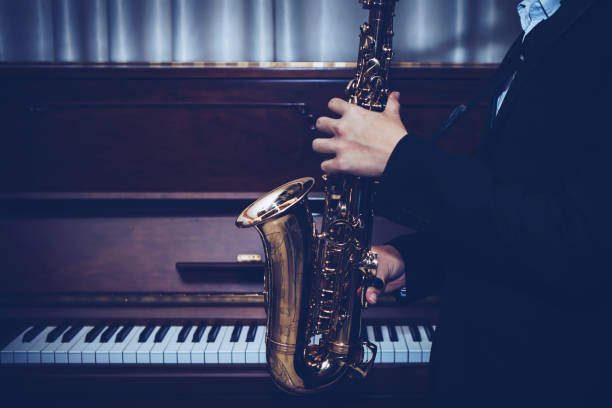 nahaufnahme von young saxophone player hände spielen altsaxophon musikinstrument über klavier hintergrund - close up musical instrument saxophone jazz stock-fotos und bilder