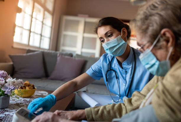 istock Home visit during lock down. Nurse is measuring blood pressure while old lady is sitting still. 1295986630